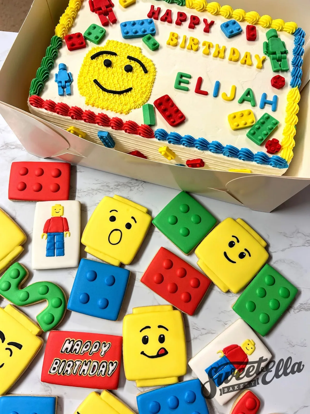 A LEGO birthday sheet cake with LEGO brick and minifigure cookies