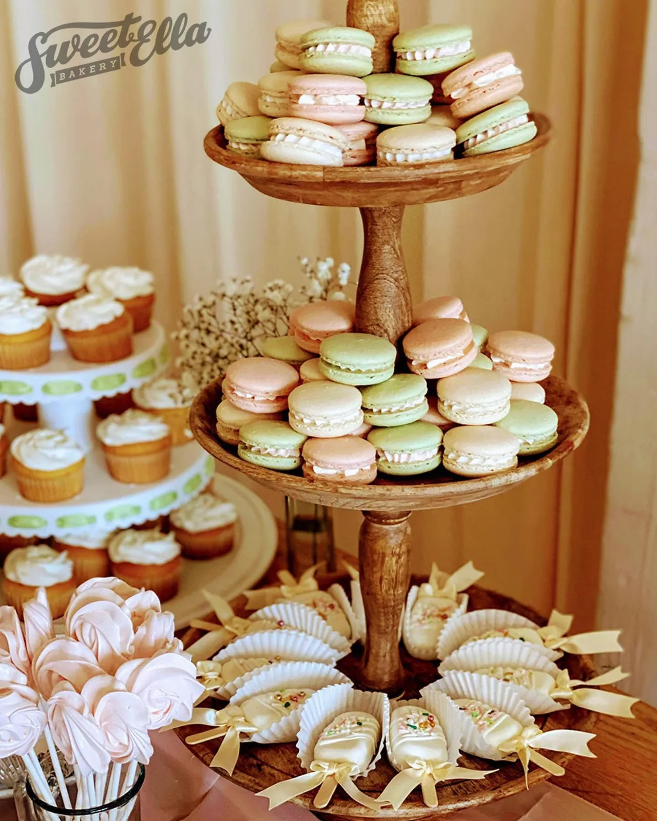 A dessert table with a tiered stand of macarons, cupcakes and cake pops