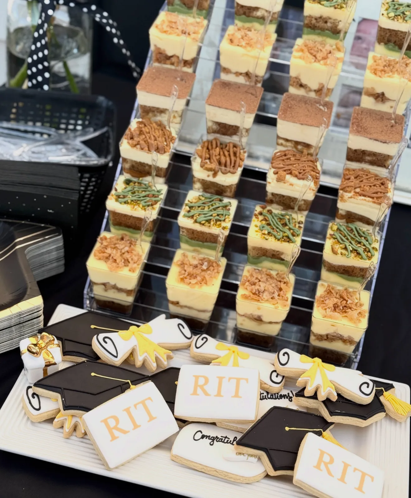 Graduation dessert cups beside cookies shaped like caps and diplomas